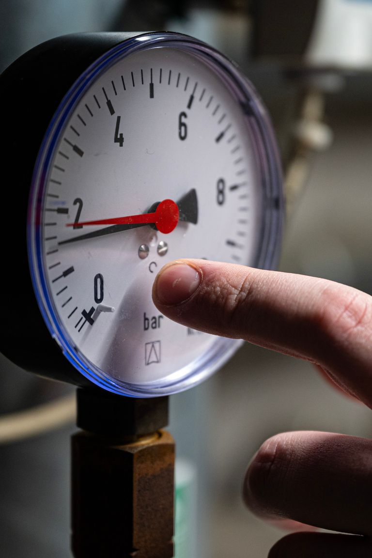 Technician checking the water pressure gauge on a hot water heating system